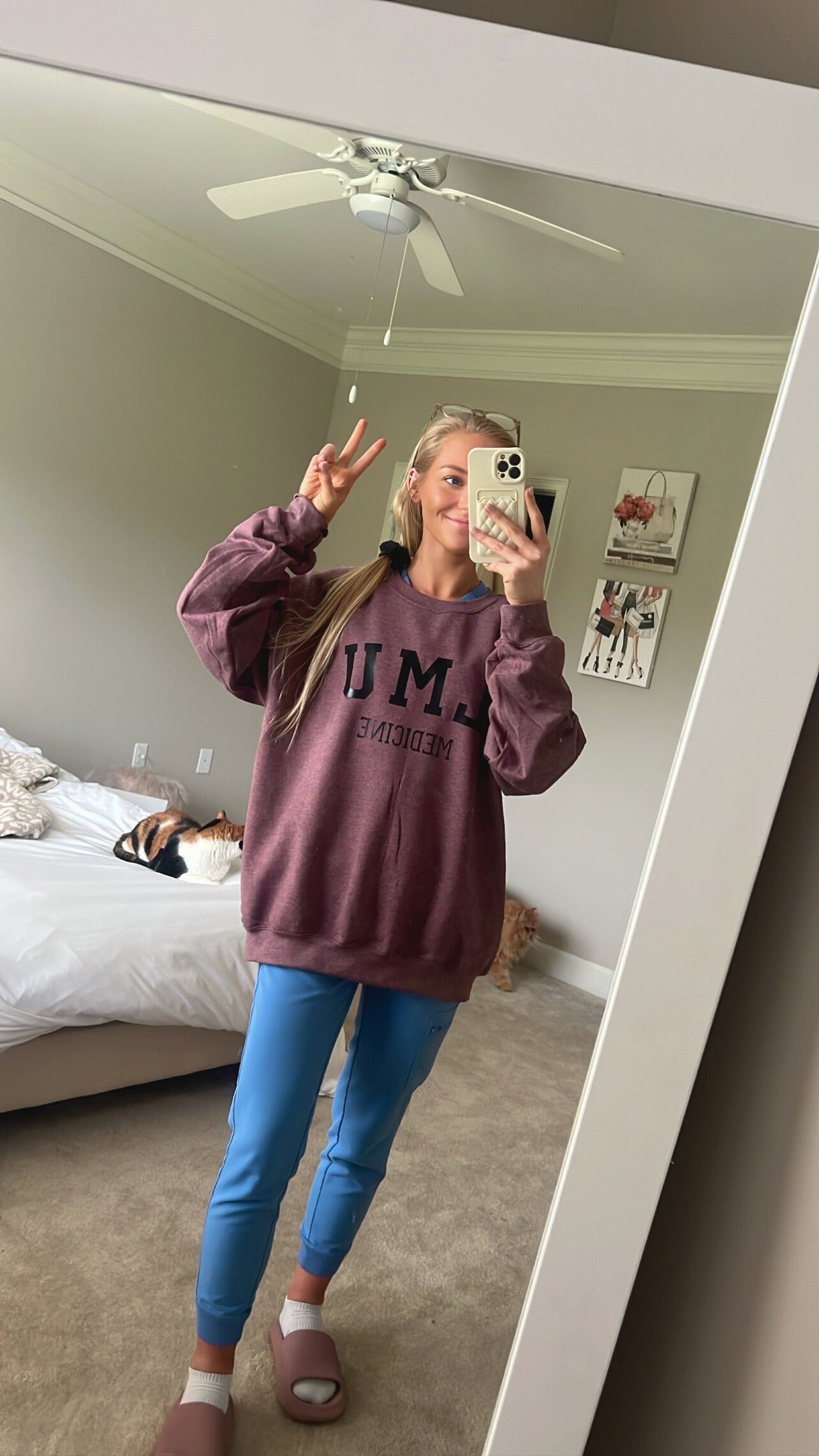 girl taking selfie in mirror with LMU crewneck and scrub pants
